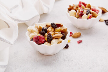 Aesthetic saucers with mixed nuts close up. Hazelnuts, cashew, raisins, cranberries, walnuts, almonds. Healthy food and snacks.
