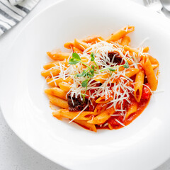 Penne pasta in tomato sauce with sun-dried tomatoes in white plate. Crop square photo. Close-up