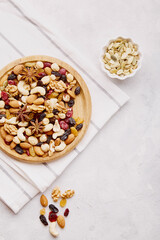 Aesthetic wooden bowl with mixed nuts from above. Healthy food and snacks. Walnut, almonds, hazelnuts and cashews. Raisins and cranberries