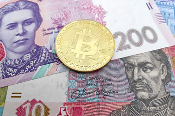 Bitcoin on top of a stack of Ukrainian Hryvnia banknotes