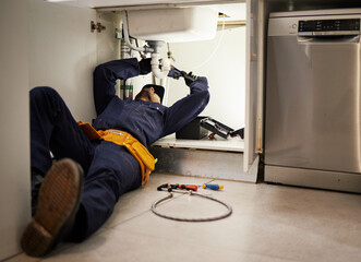 Kitchen, maintenance and renovation with a plumber on the floor of a home to fix a leak, issue or...
