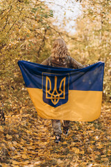 Naklejka premium A beautiful Ukrainian woman with a Ukrainian flag on her shoulders.