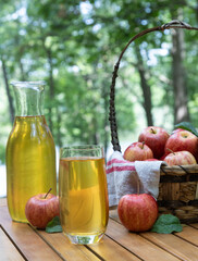 Apple juice in glass and carafe with fresh red apples