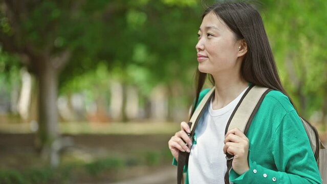 Young chinese woman tourist wearing backpack smiling at park