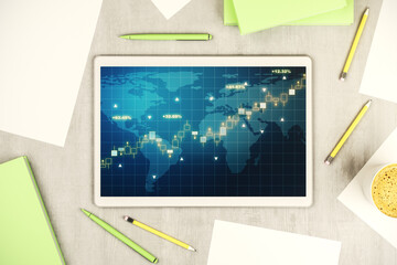 Modern digital tablet display with abstract creative financial graph and world map, financial and trading concept. Top view. 3D Rendering