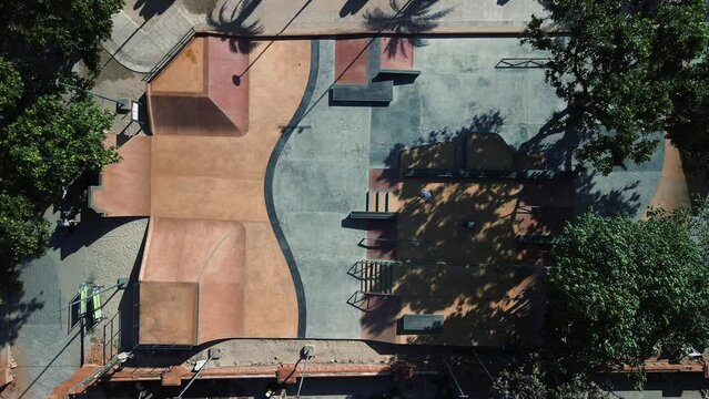 Top view of a skate park in Bali where a father teaches his son how to ride a skateboard. Skatepark on the ocean in a warm tropical country. - Powered by Adobe