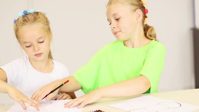 Two sisters draw a picture in a lesson at school, the concept of the development of children of primary school age. 