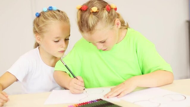 Two sisters draw a picture in a lesson at school, the concept of the development of children of primary school age. 