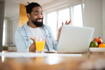 Happy black man having a video call over laptop at home