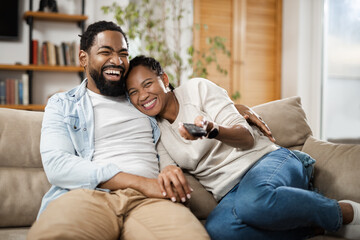 Happy African American couple watching TV on sofa in the living room