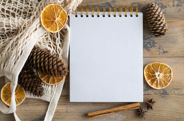 Notepad with copy space on the wooden background and natural Christmas decoration. Mockup. Eco...