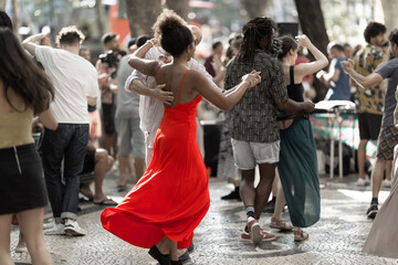 Couples dancing on the street - a woman wearing red bright dress in the centre