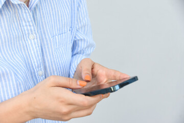 Business woman, holds smartphone in her hands against white wall .