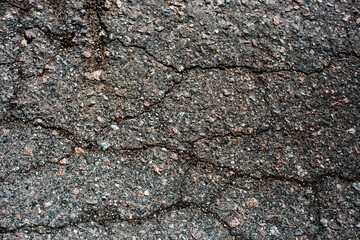 A network of black cracks on the asphalt surface. Road texture with weathered surface, showcasing the effects of time and wear