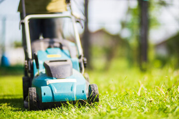 Fototapeta premium Lawn mover on green grass in modern garden or backyard. Machine for cutting lawns. Gardening care tools and equipment