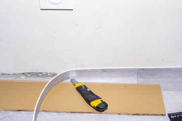 Laying of the floor covering in the apartment. Pruning of excess linoleum along the wall with a...