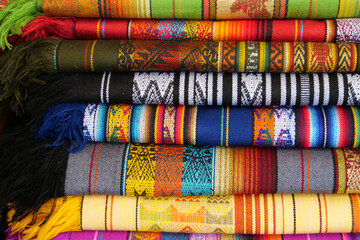 Brightly colored folded traditional fabric for sale at Otavalo market in Ecuador