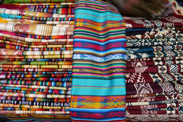 Brightly colored folded traditional fabric for sale at Otavalo market in Ecuador