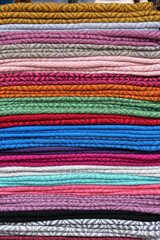 Folded colourful scarves woven from alpaca wool for sale at Otavalo market, Ecuador