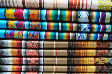 Close up of brightly colored folded traditional fabric for sale at Otavalo market in Ecuador