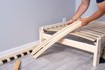 Bed planks in the hands of a furniture assembler. bed lamella