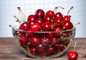 Ripe red cherries in a glass cup on the table.