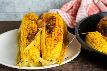 Grilled corn on the cob with sauce on a plate.