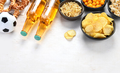 Beer bootles,  snacks and ball on  table.