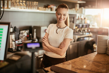 Portrait of a young female barista looking at the camera while working behind the counter at a cafe