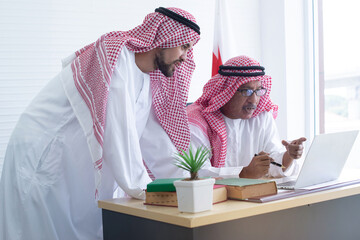 Arab businessman using laptop and discussing project at workplace, teamwork concept