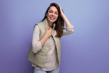 caucasian young brunette woman with hair below her shoulders smiles and poses against the background with copy space