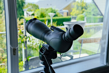Modern telescope at home next to window