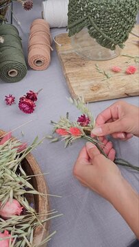 Frau bindet Trockenblumen zu einem Kranz, getrocknete Blumen, vertical Video
