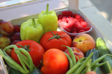 Wooden crate full of healthy seasonal fruit and vegetable, in the garden. Selective focus.