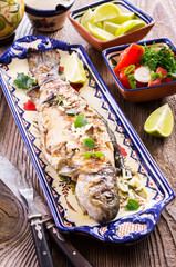 Barbecue Atlantic brown trout with tomato salad and garlic served as close-up on a rustic design plate