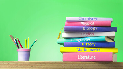 School colourfull textbooks on the table. Basic school subjects mathematics, literature, physic,s chemistry and pencils pens in a glass