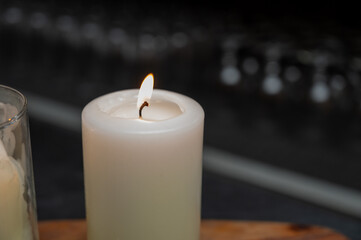 isolated lit candle with glassware in the background
