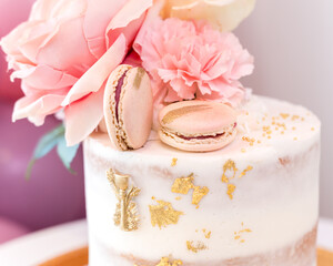 Obraz na płótnie Canvas Gold and pink cake with macaroons and gold leaf decoration