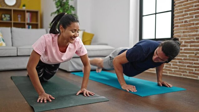 Man and woman couple training push up smiling at home