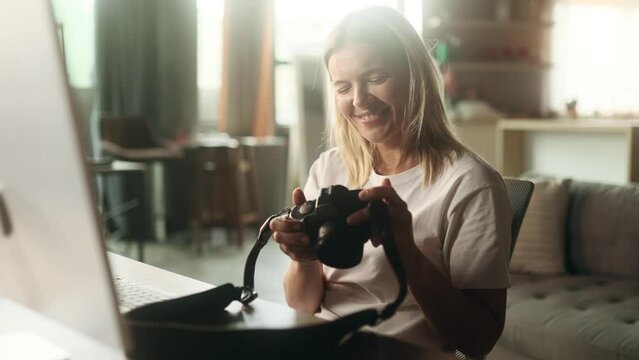 Portrait Of Pretty Mature Woman Photographer Hold Digital Camera Looking At Screen Choosing Photos For Editing While Sitting In Front Of Computer At Home Workplace