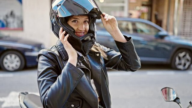 Young blonde woman wearing motorcycle helmet doing thumb up gesture at street