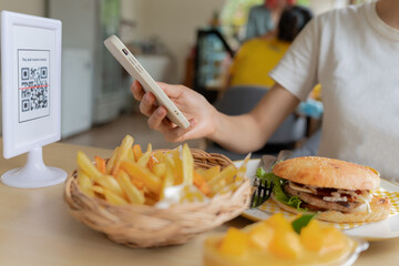 Woman use smartphone to scan QR code for order menu in cafe restaurant with a digital delivery. Choose menu and order accumulate discount. E wallet, technology, pay online, credit card, bank app.