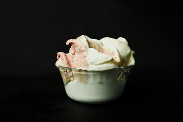 Strawberry ice cream in a bowl on a black background.