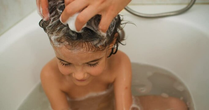 Bath Time Delight: Creating Cherished Memories as a Loving Mother Gently Washes Her Child's Hair with Bubbles of Joy. High quality 4k footage