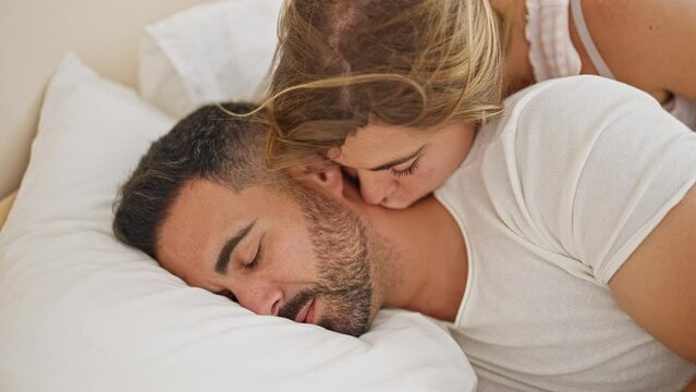 Man and woman couple lying on bed kissing while sleeping at bedroom