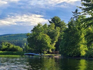 Obraz premium AI-generated illustration of a lake with a motorboat moored near the shore with lush greenery.