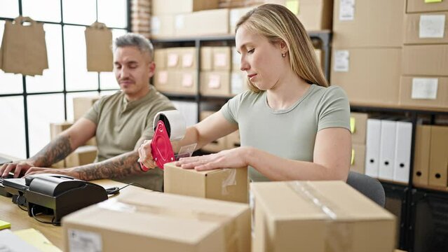 Man and woman ecommerce business workers working packing cardboard box at office