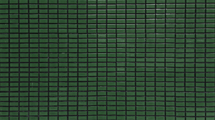 close up dark green colored mosaic wall tiles. ceramic tiles in rectangle pattern, emerald colored. vintage green mosaic kitchen wall pattern used as background.