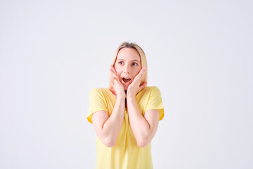 blonde girl with surprised face with hands on face in yellow t-shirt on white background