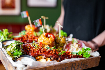 waiter hold Grilled smoked pork ribs with french fries, onion rings, vegetables and sauce